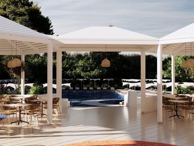 Moderní venkovní prostor s bazénem, slunečníky a stoly na terase cestovního motelu.