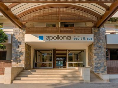 Eingang eines Hotels mit Treppen, Holzüberdachung und Schild 'apollonia resort & spa'.