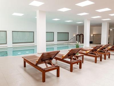 Innenpoolbereich mit hölzernen Liegestühlen und großen Fenstern an der Wand.