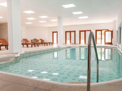 Helles Hallenbad mit Liegestühlen und großen Fenstern
