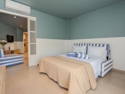 Schlafzimmer mit gestreiftem Bett, beiger Decke und blau-weißen Wänden in einem Hotelzimmer.