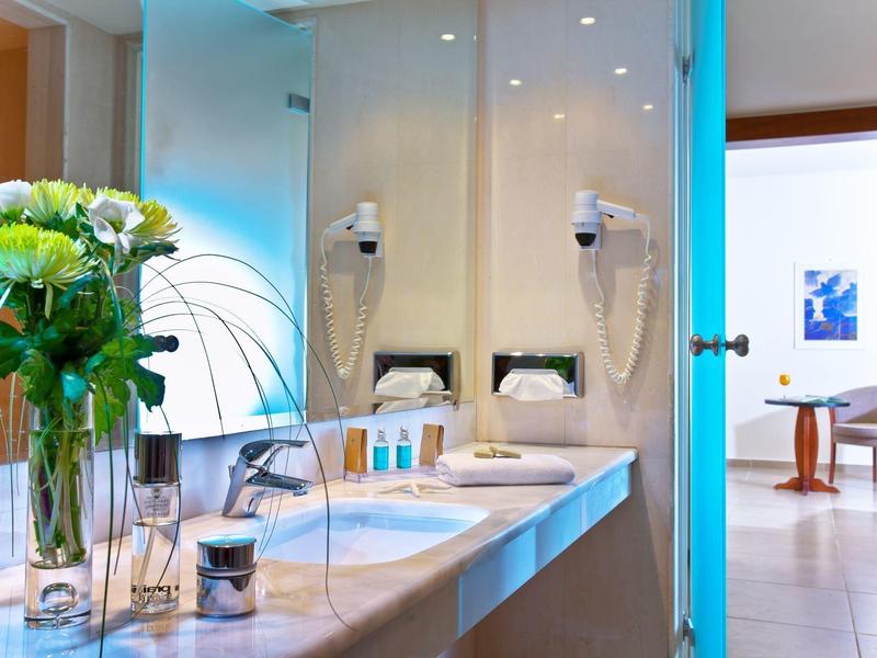 Světelná koupelna se dvěma umyvadly, zrcadlem a květinovými vázy na pultu.