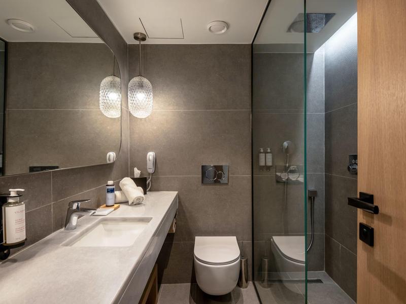 Moderní koupelna se šedými stěnami, dvojitým umyvadlem a skleněnou sprchou.