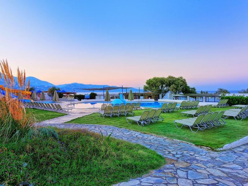 Bazénová oblast s lehátky a výhledem na hory za jasné oblohy při západu slunce.