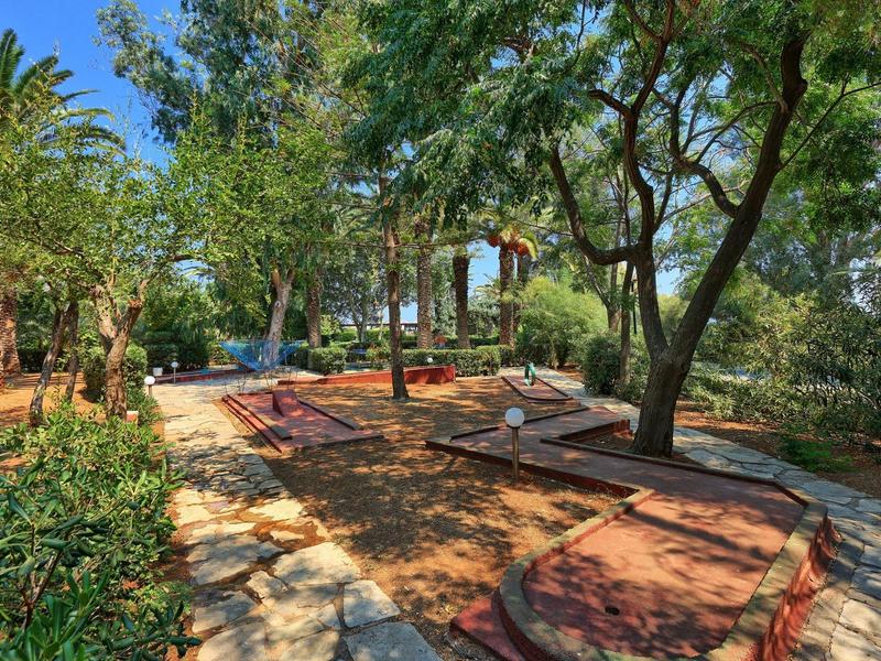 Venkovní minigolfové hřiště obklopené stromy a rostlinami v hotelové zahradě