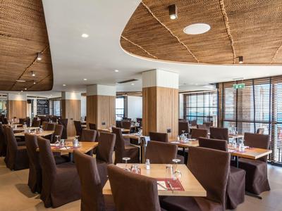 Modern dining room with brown chairs and wooden tables, featuring unique ceiling design.