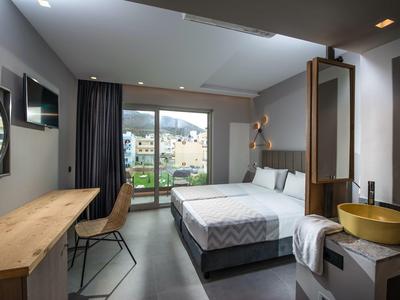 Modern hotel room with a double bed, desk, chair, balcony, and mountain view.