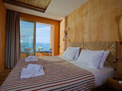 Cozy bedroom with striped bedspread, towels, and a balcony overlooking the sea.