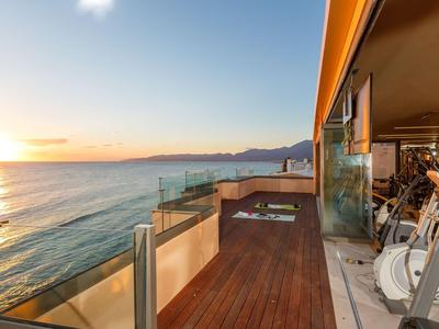 Balcone con pavimento in legno e cyclette con vista sul mare al tramonto