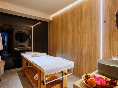 Modern massage room with wooden walls, white table, and relaxing lighting.