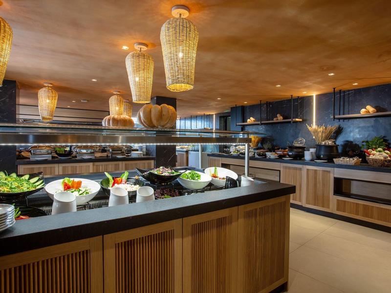 Modern buffet area with black countertops, wooden cabinetry, and hanging woven light fixtures.