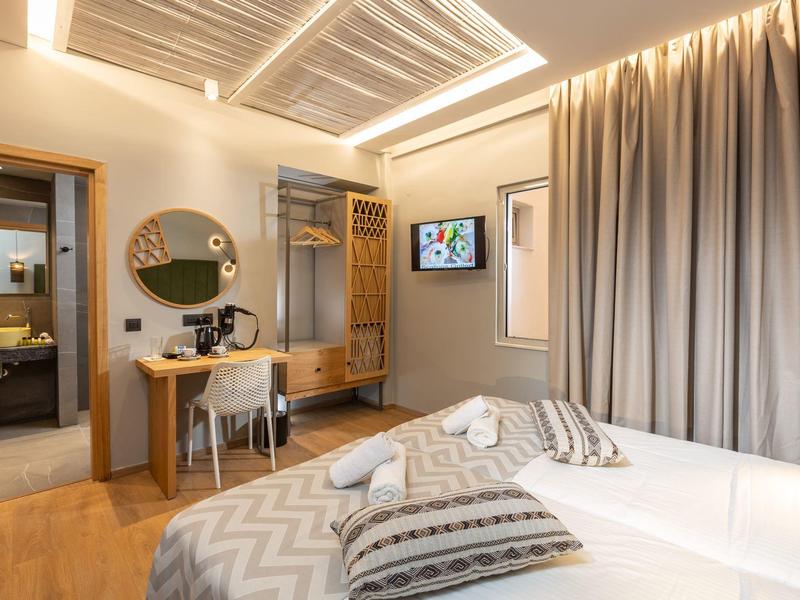 Cozy hotel room with double bed, desk, chair, mirror, and curtains.