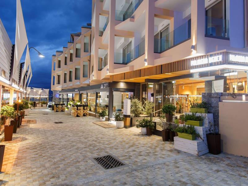 Modern hotel entrance at dusk with outdoor seating and warm lighting.