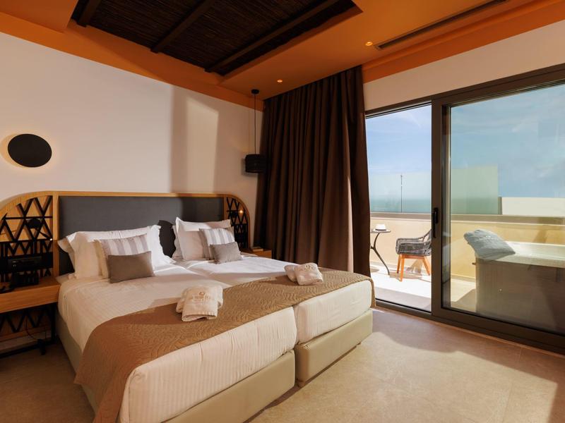 Modern hotel room with two single beds and access to a terrace with sea view.