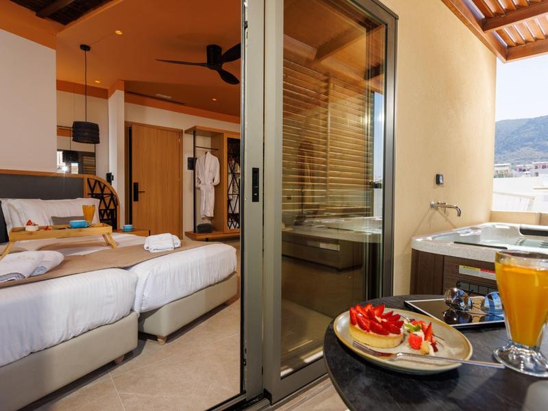 Hotel room with bed, open door to balcony with breakfast and mountain view.