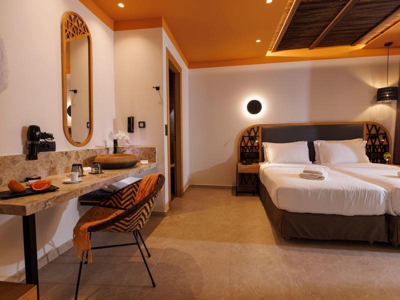 Modern hotel room with two beds, a desk, and warm lighting