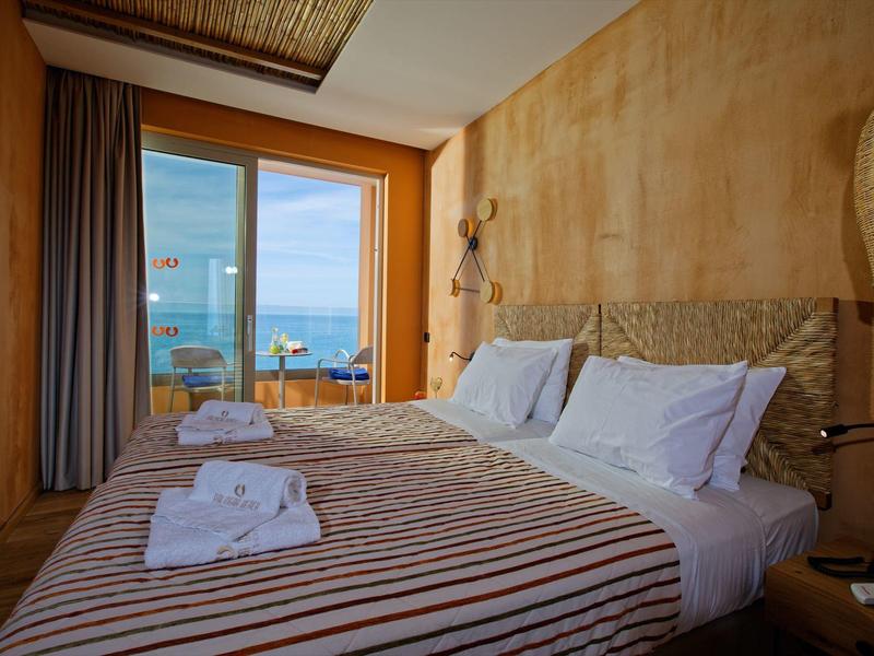 Cozy bedroom with striped bedspread, towels, and a balcony overlooking the sea.