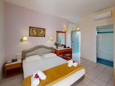 Gemütliches Schlafzimmer mit Doppelbett, braunem Bettlaken, Nachttischen und hellem Fliesenboden.