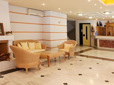 Helle Hotellobby mit gemütlichen Sesseln, Kamin und Empfangstresen.