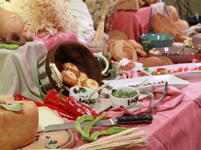 Bunte Kräuter, Gewürze und Knoblauch liegen auf einem Tisch mit rosa Tischtuch.