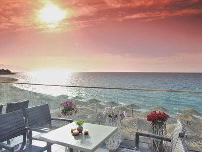 Zonsondergang boven de zee met terras en tafels van een hotel.