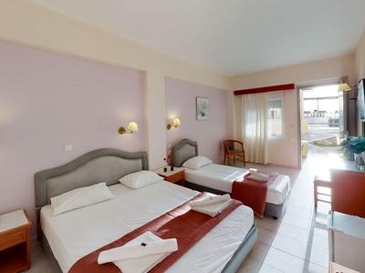 Hotelkamer met twee bedden, televisie, tafel en balkon met daglicht.