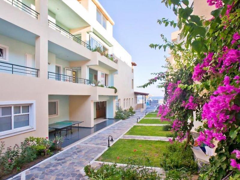 Moderner Wohnkomplex mit blühendem Bougainvillea und gepflegtem Gartenweg bei Tageslicht.