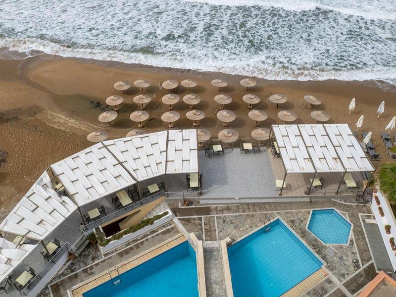 Drei blaue Pools, Sonnenschirme und Sandstrand mit Wellen, Luftaufnahme eines Resorts.