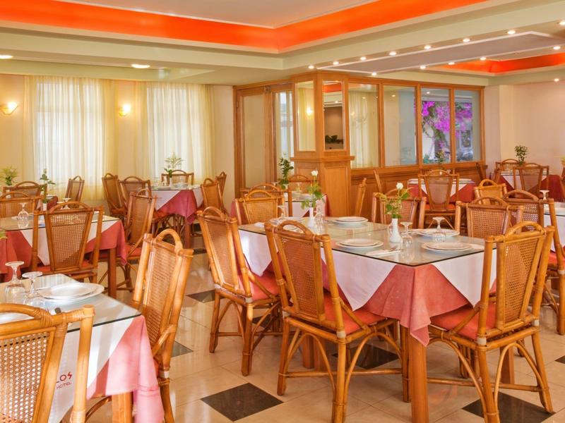 Großer heller Speisesaal mit Holzstühlen, weißen Tischdecken und warmem orangem Licht.