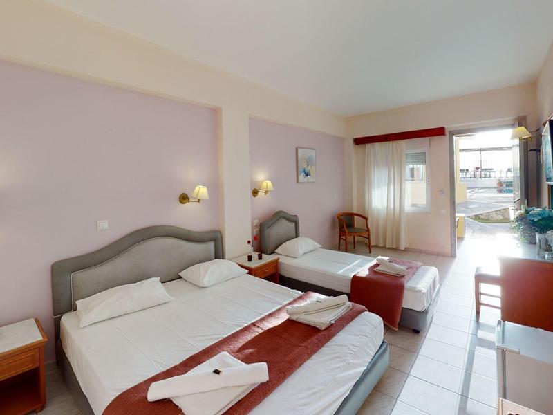 Hotelzimmer mit zwei Betten, lila Wänden, Nachttischen, Klimaanlage und Blick auf Balkon.