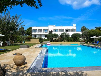 Grande piscina all'aperto davanti a un edificio dell'hotel imbiancato a calce in una giornata di sole