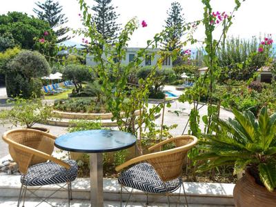Vista di una terrazza con tavoli rotondi, sedie e un rigoglioso paesaggio verde sullo sfondo.