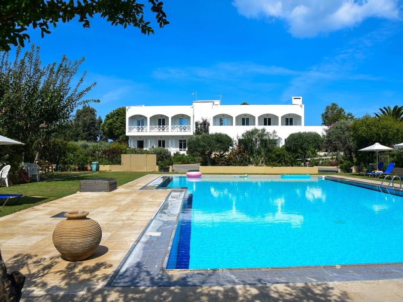 Krásná hotelová budova s velkým lákavým bazénem a slunečníky pod modrou oblohou.