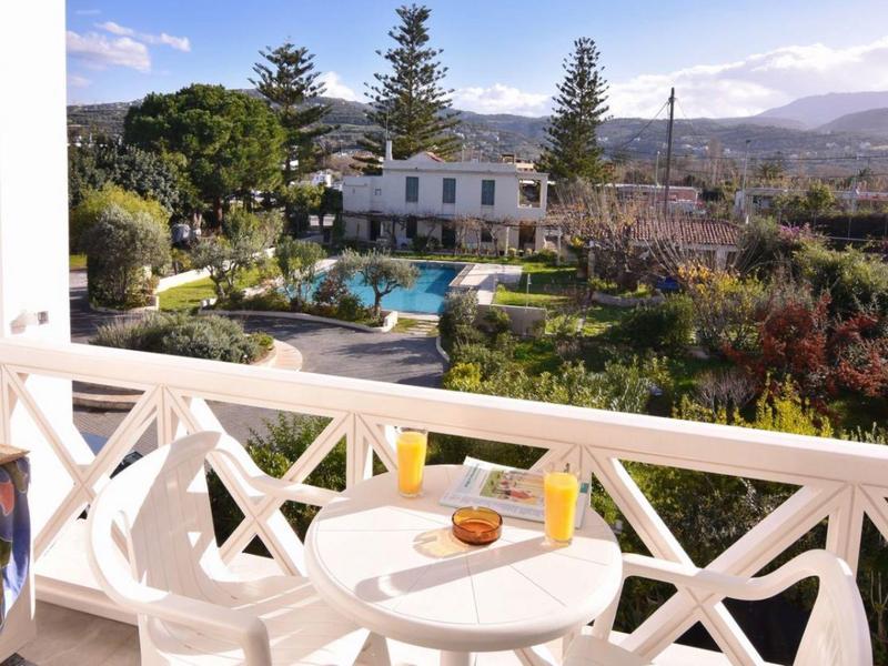 Balkon se stolem a židlemi s výhledem na zahradu a bazén s horským pozadím