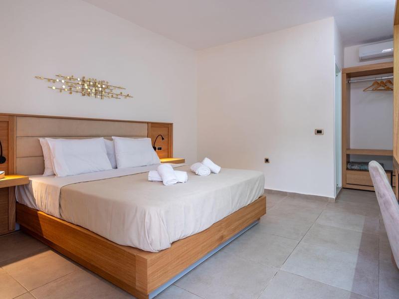 Modern hotel room with double bed, bedside tables, wall decor, and shower towels.