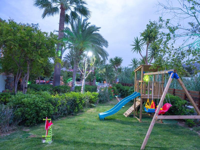Playground with swing, slide, and trees in a garden area