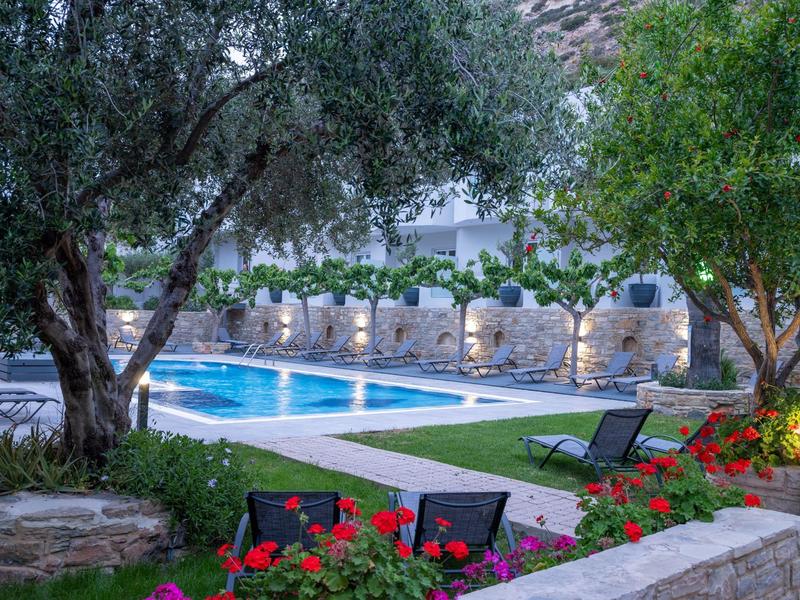 Illuminated pool area in the evening with lounge chairs and trees in a hotel garden