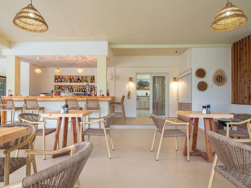 Bright and modern bar and dining area with wooden furniture and stylish pendant lights.