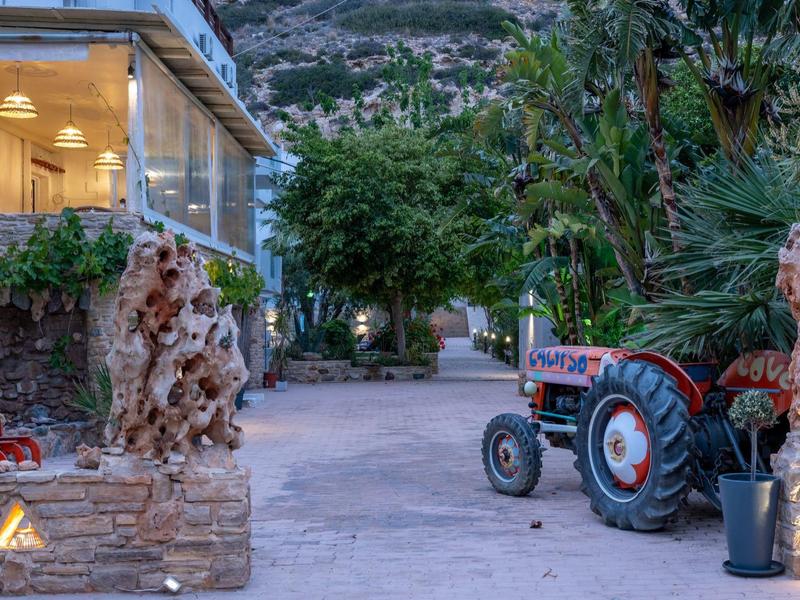 A tractor stands on a path beside a stone building decorated with plants in the hotel garden.