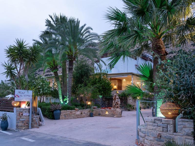 Hotel grounds with palm trees, illuminated paths, and inviting entrance at dusk.