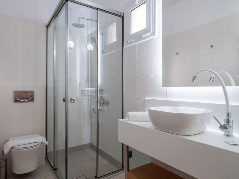 Modern bathroom with glass shower, countertop basin, and toilet.