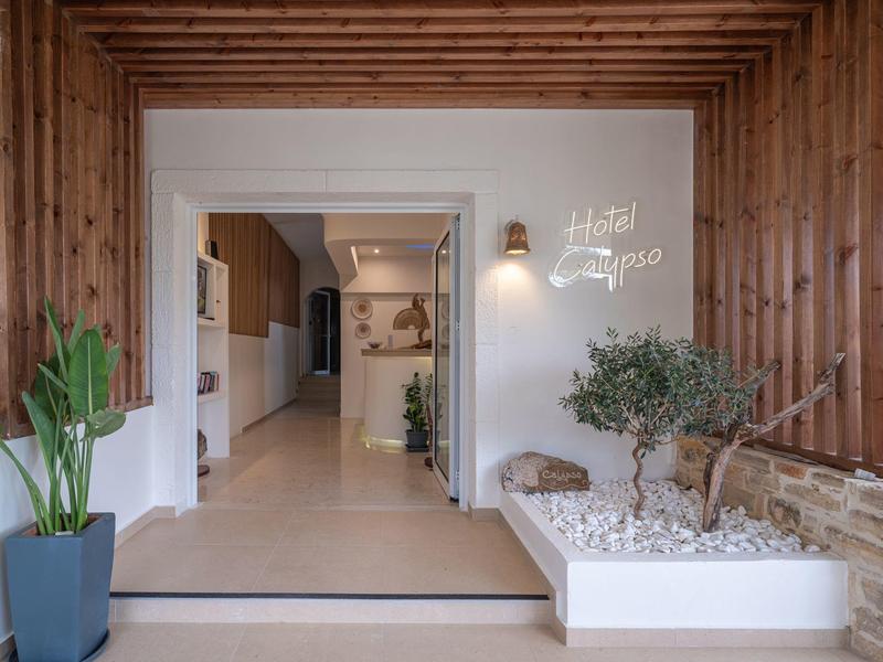 Modern entrance area with wooden wall, plants, and white gravel in a hotel.