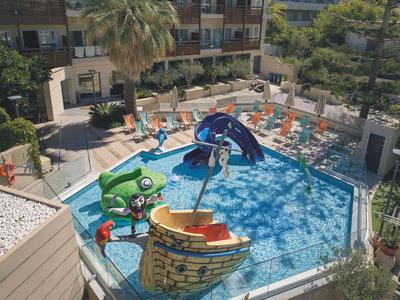 Children's pool with play structures shaped like a boat and an animal, surrounded by sun loungers.