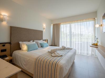 Lichte hotelkamer met tweepersoonsbed, grote ramen en modern, minimalistisch ontwerp.