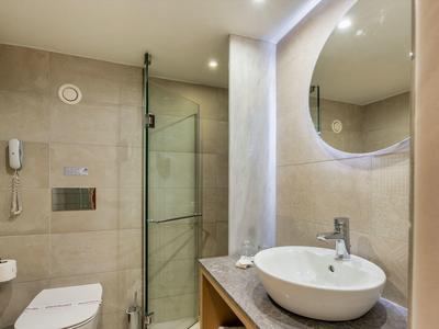 Modern badkamer met ronde spiegel, glazen douche en witte wastafel.