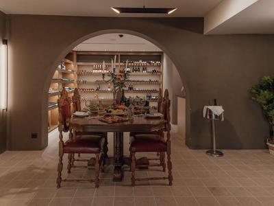 Gezellige eetruimte met houten stoelen en een boogvormige doorgang naar een keuken met planken.