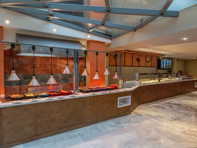 Buffet area with various dishes in heated containers and modern lighting.