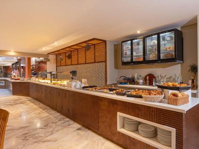 Buffetgedeelte met warme verlichting, witte marmeren vloer en moderne toonbank met eten en servies.