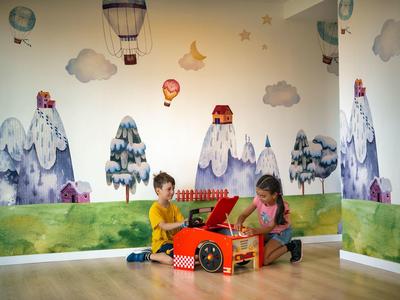 Kinderen spelen op houten vloer voor een muur met bergen en luchtballon muurschilderingen.