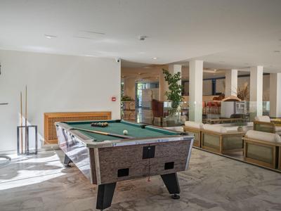 Modern hotel lounge with pool table and comfortable seating areas in a bright room.